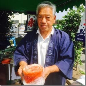 ハッピを着た男性がトマトかき氷を両手で持っている写真