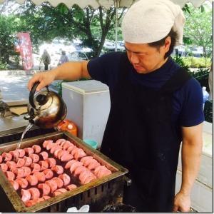 男性がやかんで水を注いで、赤いトマト餃子を焼いている様子の写真