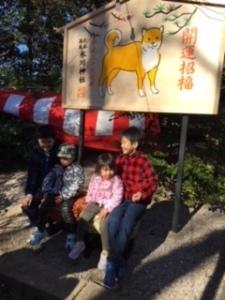 干支のイラストが載っている大きな絵馬の前で座っている子供4人の写真