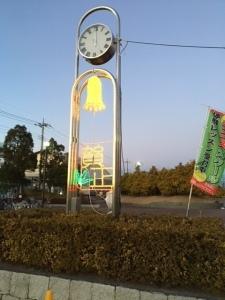 横に並んだ植栽の奥に立つ時計台の写真