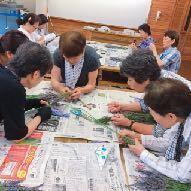 机に新聞紙を広げ熱心に制作をしている参加者達の写真
