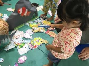 紙で作った魚つりをしている小さな女の子の写真