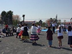 輪になりフォークダンスを楽しむたくさんの人々の写真