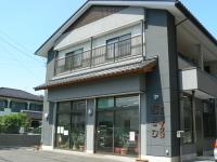 白とグレーを基調とした2階建てのむさし製菓外観写真