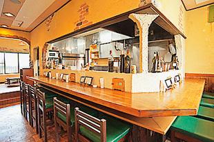厨房が見えるカウンターと奥に座敷があるクッチーナD店内の写真