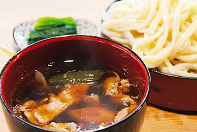 うどんと豚肉やネギが入っているうどんのつゆの写真
