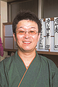 緑の着物を着た店主の谷口さんが笑顔で写っている写真
