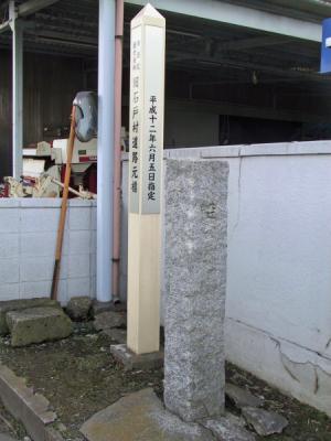 細い旧石戸村道路元標と隣に案内の白い塔が建てられている写真