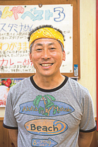 黄色いバンダナを頭に巻いた、笑顔の店主保角さんの写真