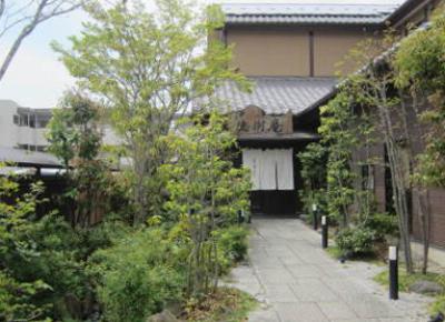 石畳の道に沿って木々の生えた和を基調とした料亭風の建物写真