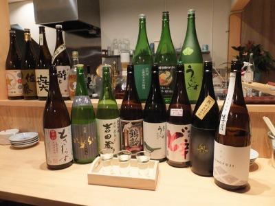 15種類ほどのお酒がカウンターに並べられている写真