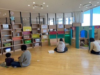 遊具の置かれた部屋で遊ぶ親子の写真