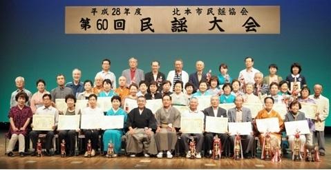 民謡大会出席者の方々が賞状やトロフィを持って写っている集合写真
