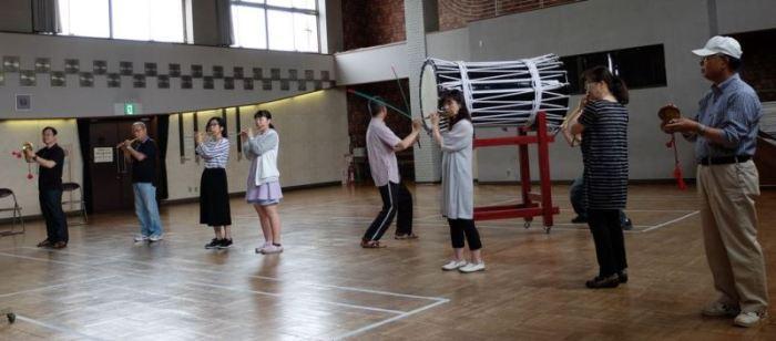 体育館で太鼓や笛などの楽器を持ちねぷた囃子の練習をしている写真