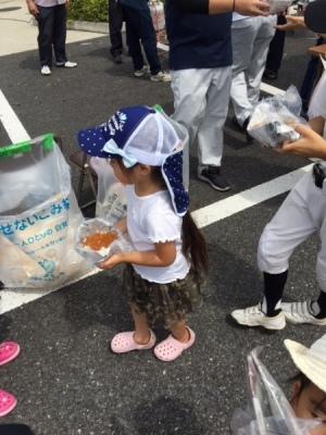 新聞紙で作成した紙のお皿にカレーをよそってもらい運ぶ女の子の写真