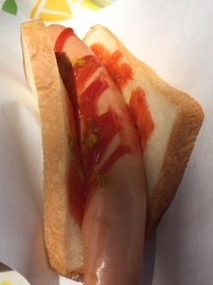 食パンにソーセージを挟んだ上にトマトソースがかかったトマトカレードッグの写真