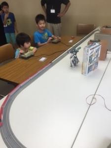 2人の子供が操縦する鉄道模型の運転体験の写真