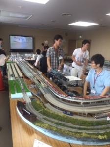 鉄道模型を眺める3人の男性の写真