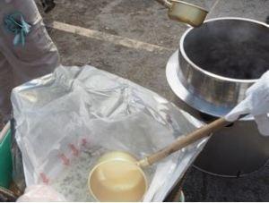 ビニールの中に入ったわかめご飯ををひしゃくですくおうとしている写真