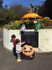 子供公園入り口の花壇前に設置された大きなかぼちゃと投稿者の2人の子供たちの写真