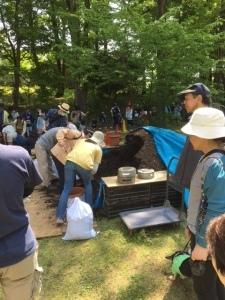 大人たちが腐葉土をすくっている様子の写真