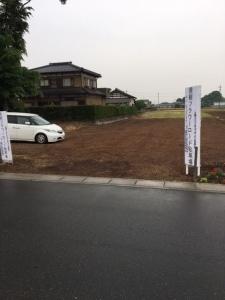 住宅の横の白い看板がある駐車場に白い車が一台止まっている写真