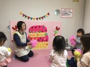 ピンクや黄色のボンボンを持っている子供3人と女性2人の写真