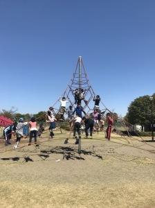 雲一つない青空の下で、遊具のジャングルジムに上る子供たちの写真