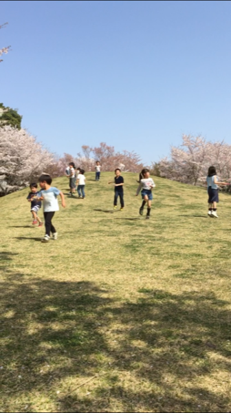 緩やかな丘の頂上から一斉に走り出すたくさんの子供たちの写真