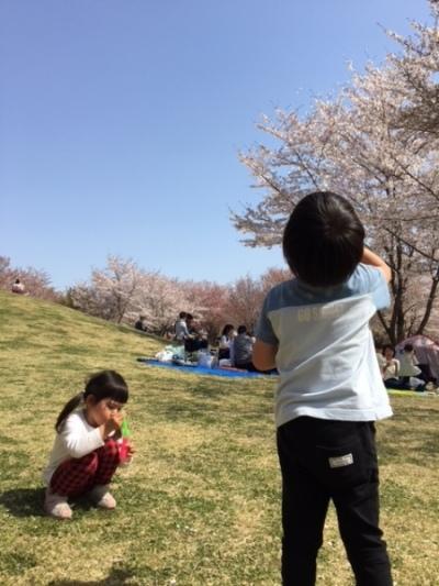 青空の下、男の子と女の子がシャボン玉で遊んでいる様子の写真