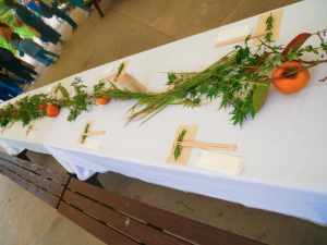 白いテーブルクロスの上に置かれた柿や秋の植物がセットされた写真