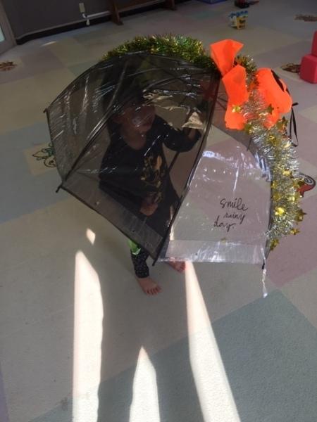 オレンジのかぼちゃとモールの飾りつけをされたグレーの透明の傘をさす女の子の写真
