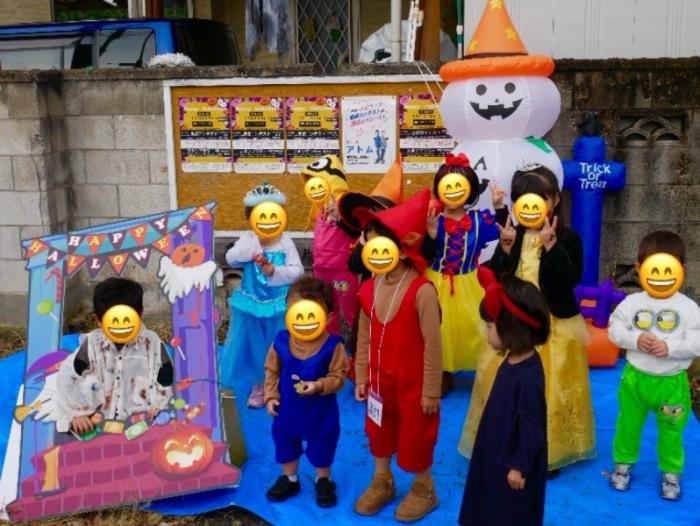 ブロックに貼られたコルクボード前に集まるハロウィンの仮装をした子供たちの写真
