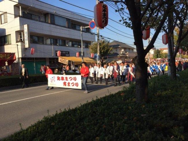 北本まつり、宵まつりと書かれた幕を持って男性たちが歩いている写真