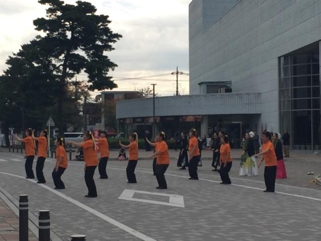 オレンジのTシャツを着た女性たちが踊っている写真