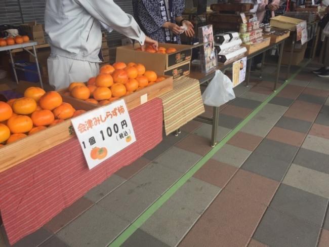 会津みしらず柿と書かれた紙が貼られたテーブルに柿が並んでいる写真