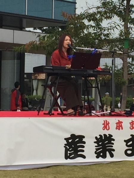 舞台の上でキーボードを弾きながら女性が歌っている写真