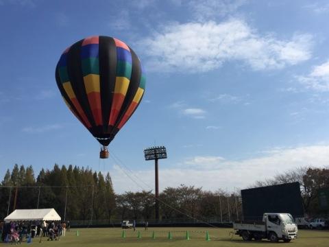 青空の下でカラフルな気球が飛ばされている写真