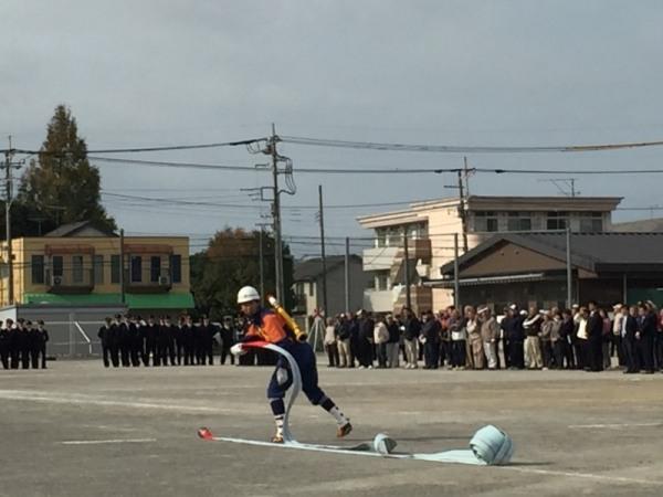 消防団の男性が地面にホースを投げている写真