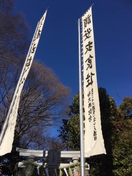 青空の下、大きな白い旗と白い鳥居、木々が並んでいる写真