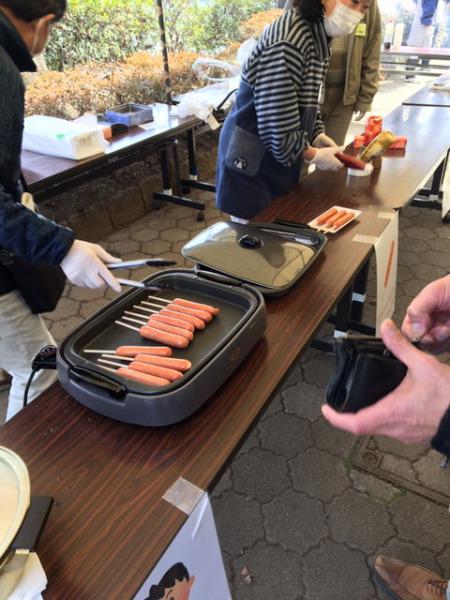 男性がホットプレートでウィンナーを焼いている様子の写真