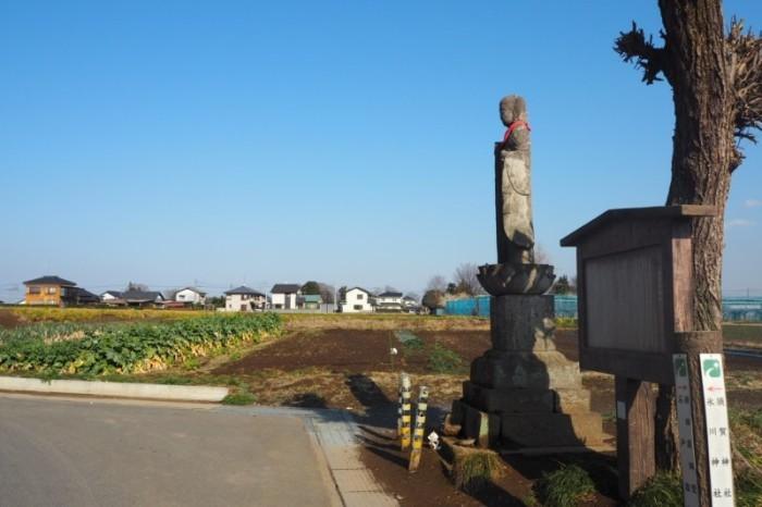 田んぼの脇道に北向き地蔵が立っている写真