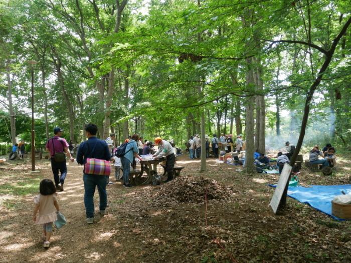 緑の森の間から日が射し、イベントを楽しむ参加者の写真