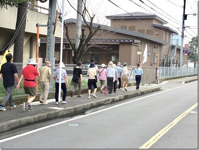 先頭の旗を持った女性に続いて歩いている参加者達の写真