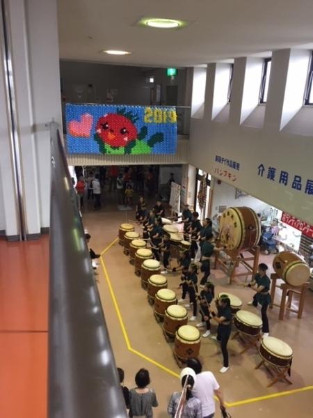 風船でできたとまちゃん壁画の下で和太鼓を演奏している様子の写真