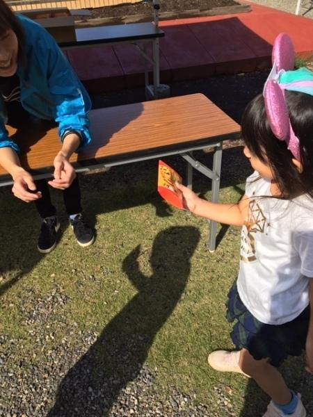 ピンクの耳をつけた女の子がお菓子をもらって喜んでいる様子の写真