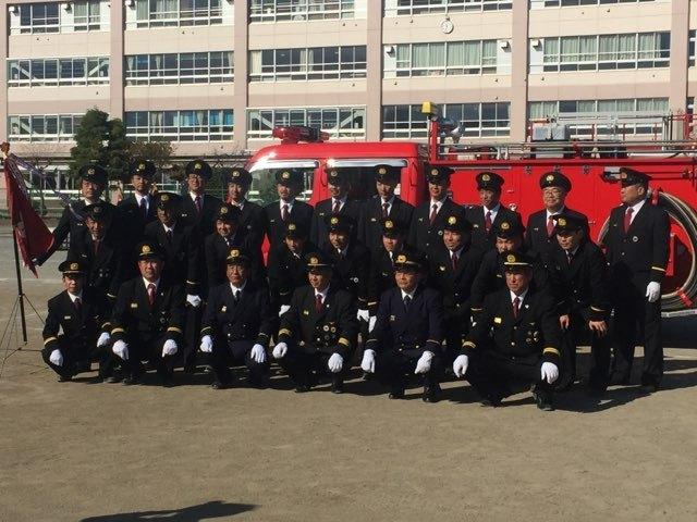 消防車の前で記念写真を撮る大勢の消防団員のアップの写真