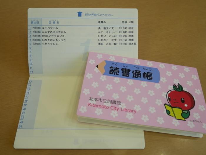 とまちゃんが描かれたピンク色の読書通帳表紙と5冊の本が記帳された通帳の写真