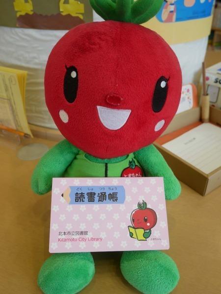 ピンク色の読書通帳を持ったとまちゃんぬいぐるみの写真