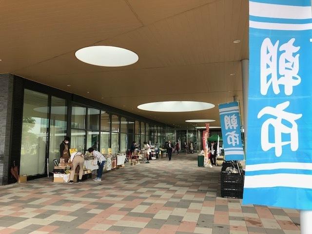 北本市役所みどりの広場前（庁舎ホール横）で朝市と書かれた水色ののぼりが立ち、新鮮野菜や名物などを販売している方々の写真